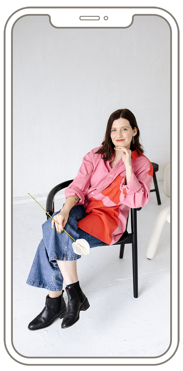 amy pearson on chair with flower and pink shirt smiling designer