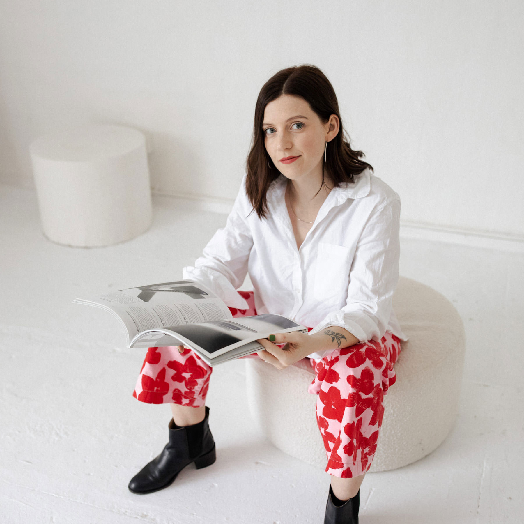 amy pearson flower jeans black boots reading magazine looking at camera